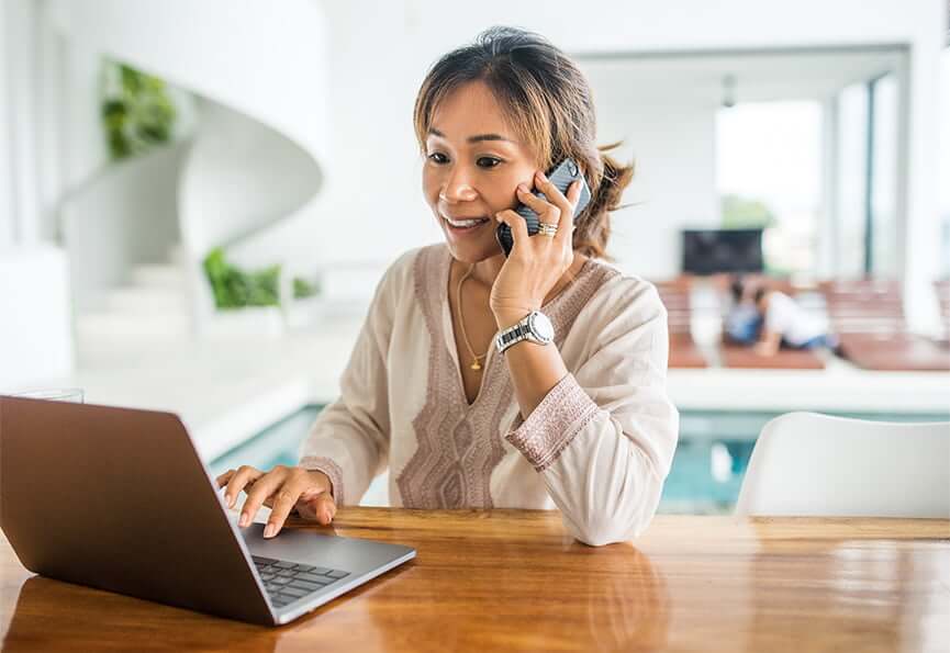 woman talking on the phone while looking at her laptop