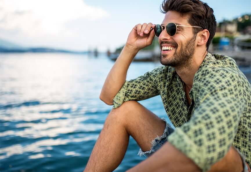 smiling man sitting next to a lake