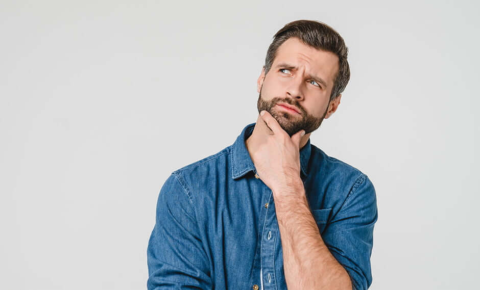 man standing in a pensive pose with his chin held in his hand