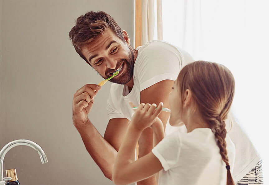 father and daughter brushing their teeth together