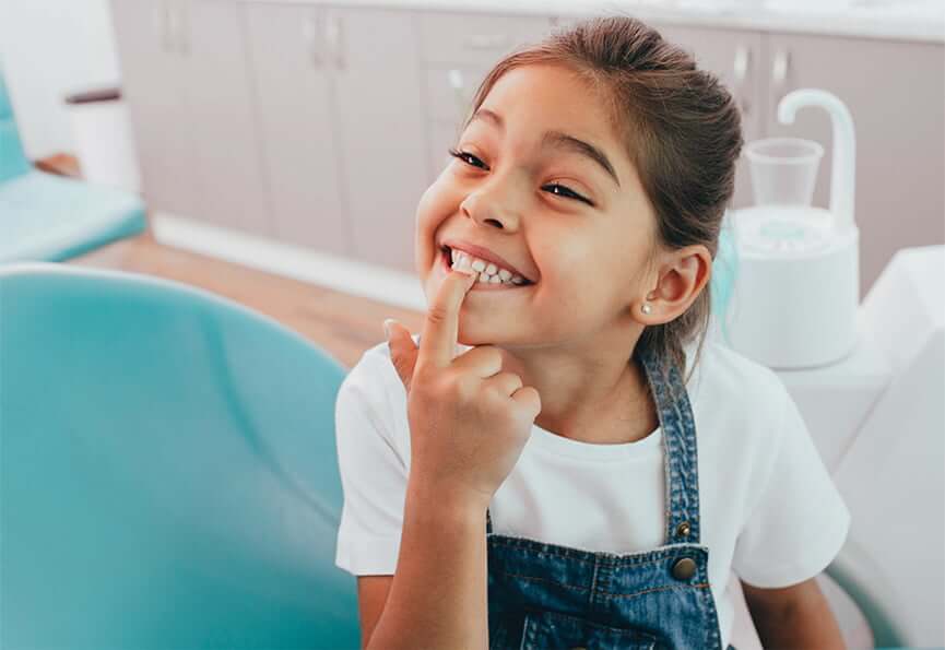 young girl pointing at her white teeth